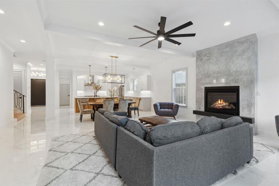 Living room with ceiling fan with notable chandelier and a fireplace