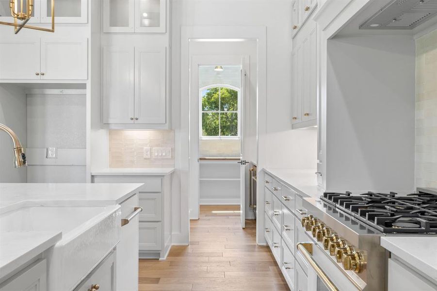 Kitchen featuring decorative backsplash, stainless steel range, light hardwood / wood-style flooring, and white cabinetry