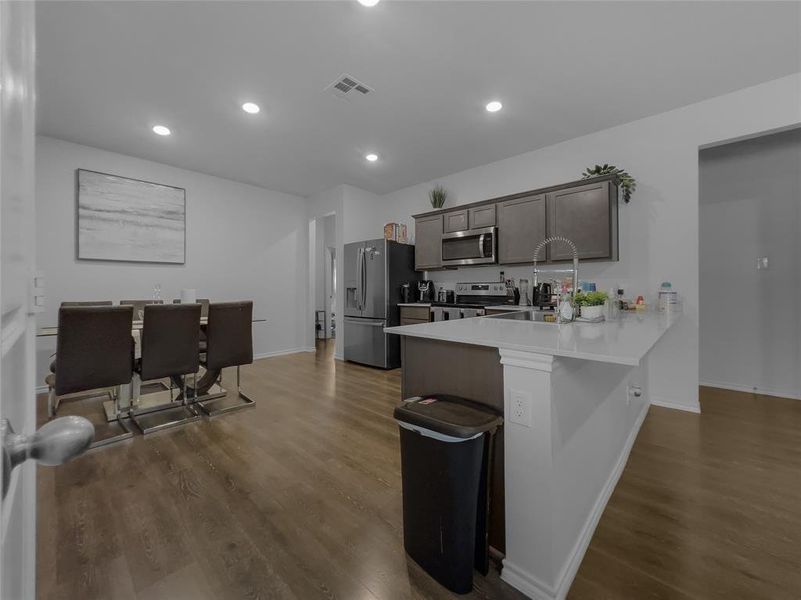 Kitchen with dark hardwood / wood-style floors, sink, kitchen peninsula, a kitchen bar, and stainless steel appliances