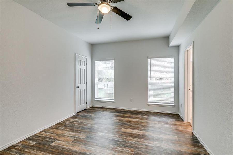 Unfurnished room with a wealth of natural light, dark wood-type flooring, and ceiling fan