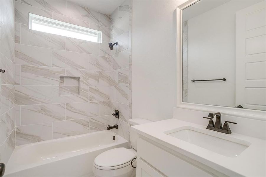 Full bathroom featuring toilet, vanity, and tiled shower / bath combo