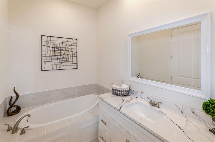 Bathroom with vanity with extensive cabinet space and a bath