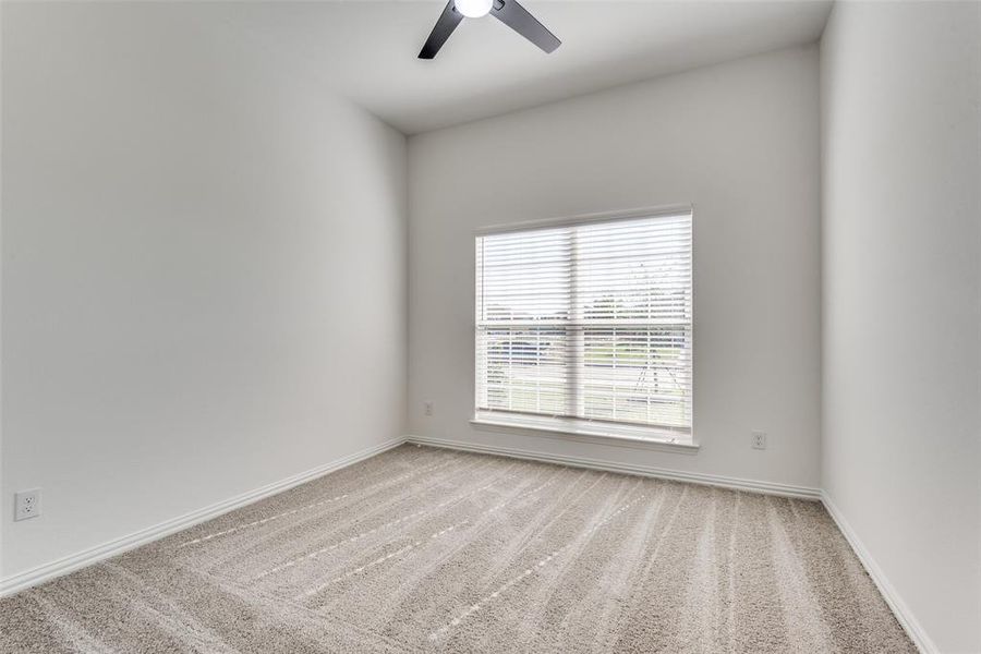 Spare room featuring light carpet and ceiling fan