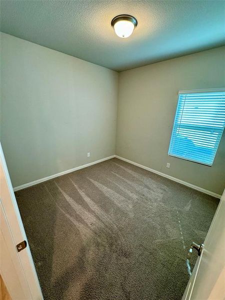 Carpeted spare room featuring a textured ceiling