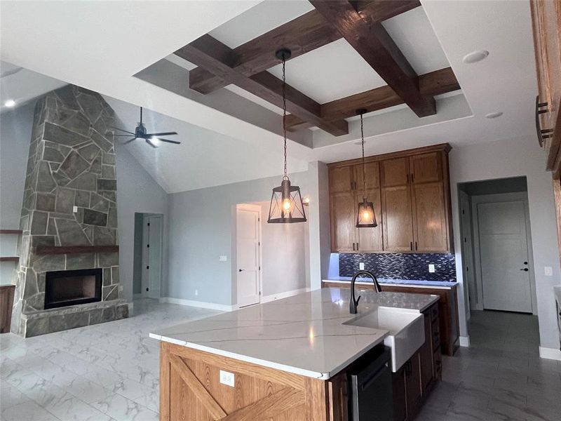 Kitchen featuring beamed ceiling, sink, a fireplace, and a kitchen island with sink