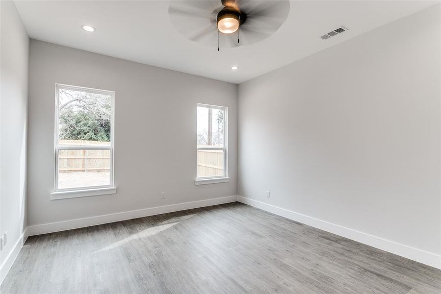 Empty room featuring ceiling fan, hardwood / wood-style floors, and a wealth of natural light
