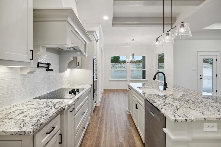 Kitchen with stainless steel dishwasher, tasteful backsplash, hardwood / wood-style floors, an island with sink, and sink