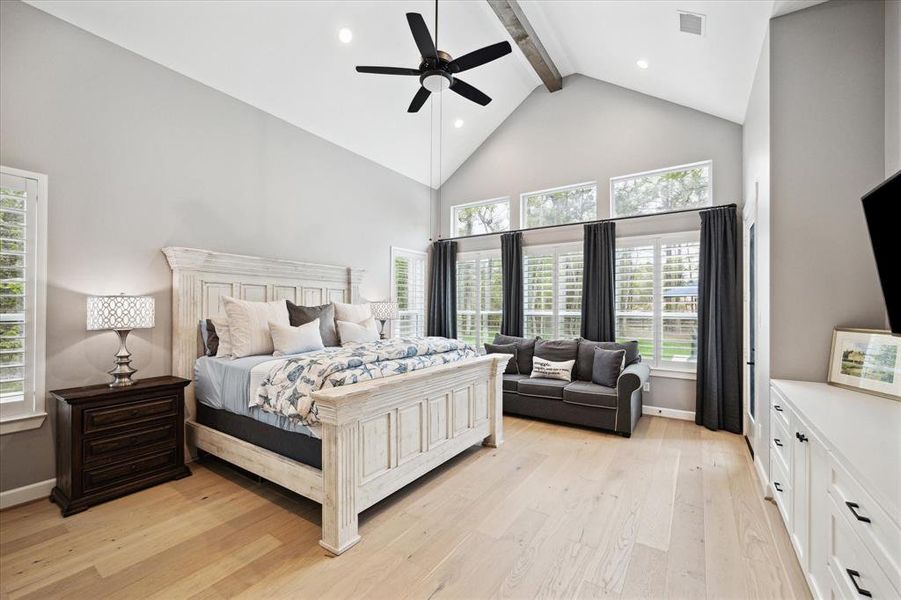 Primary bedroom with engineered wood floors, vaulted with a wood beam, recessed lighting, ceiling fan and plantation shutters.
