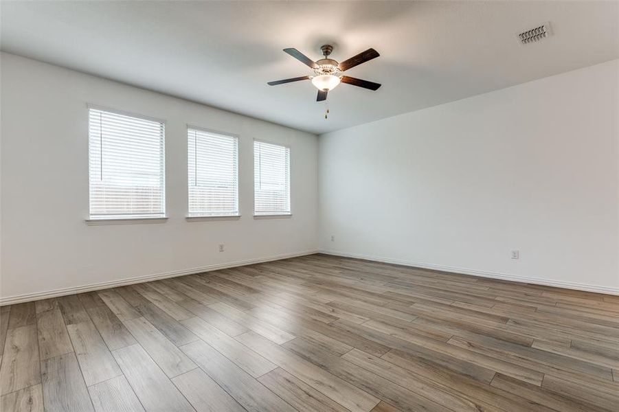 Empty room with ceiling fan and light wood-type flooring