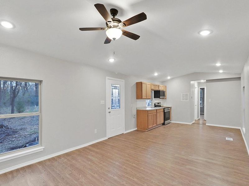 Unfurnished living room with ceiling fan, lofted ceiling, and light hardwood / wood-style floors