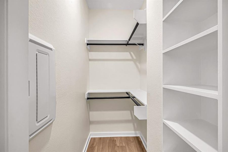 Primary closet with hanging space and built in shelves.