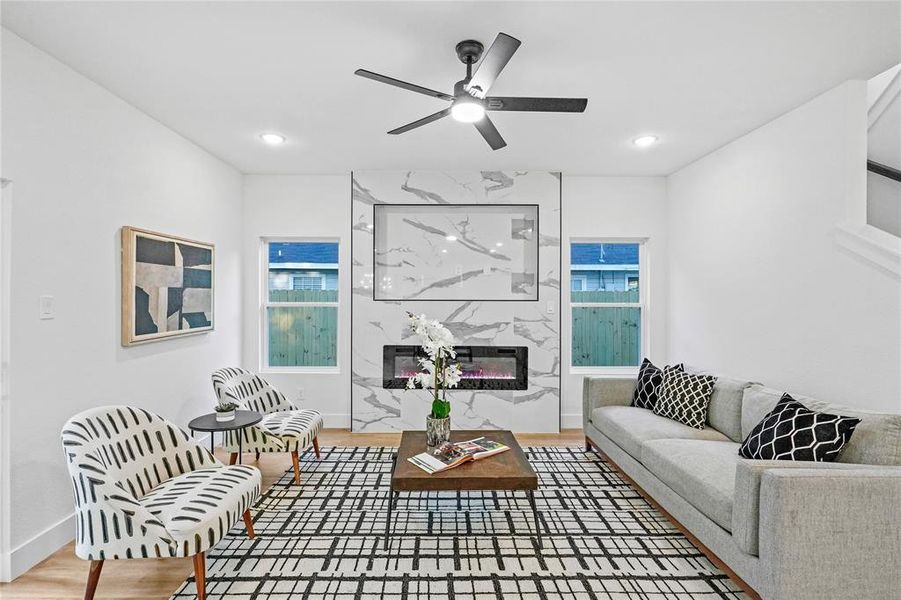 Living room with a premium fireplace, hardwood / wood-style floors, and ceiling fan