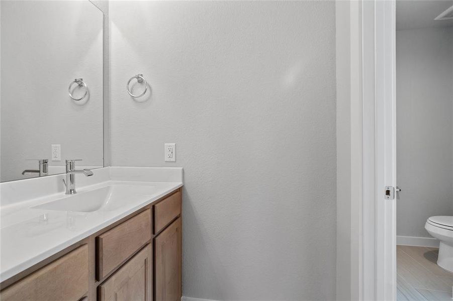 This jack and jill set up is perfect for a secondary bathroom, with its own private sink on either side. Bathroom features tile flooring, bath/shower combo with tile surround, stained wood cabinets, beautiful light countertops, mirrow, dark, sleek features and modern finishes.