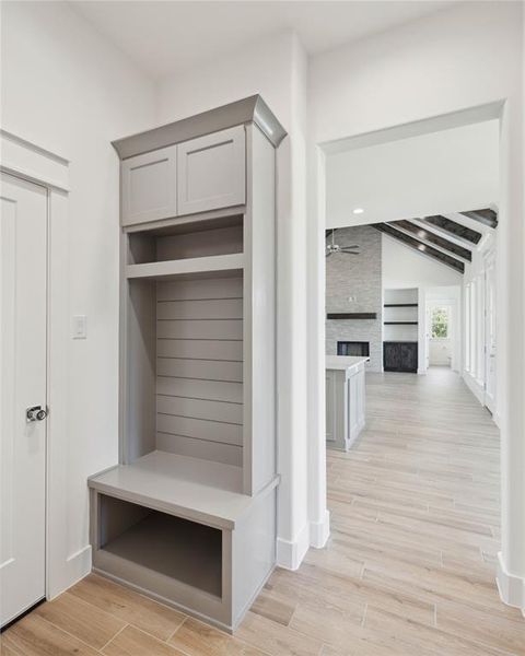 Mudroom with light wood-type flooring, a fireplace, ceiling fan, and beam ceiling