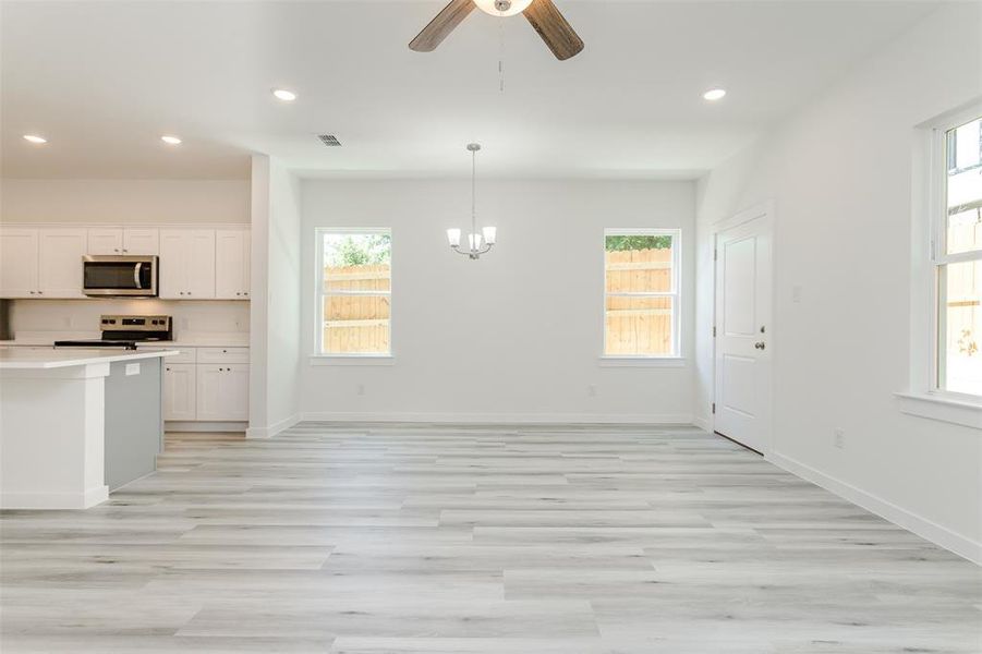 Kitchen with electric range, plenty of natural light, white cabinets, and light wood-type flooring