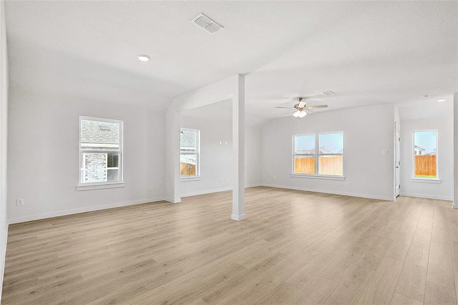 Unfurnished living room featuring a wealth of natural light, light wood-type flooring, vaulted ceiling, and ceiling fan