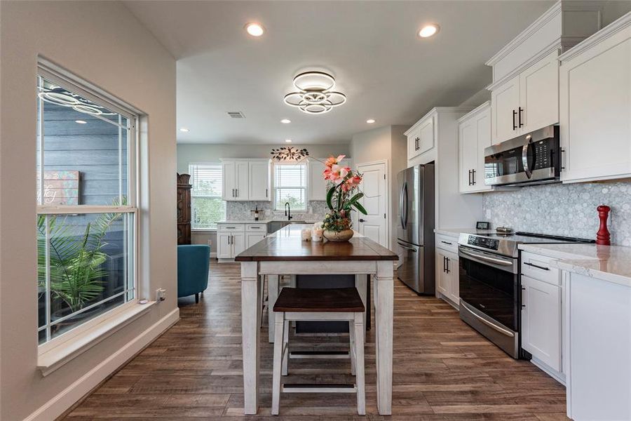 The kitchen is a culinary dream, complete with a quartz countertop, island seating, a stunning marble backsplash, and a wine refrigerator