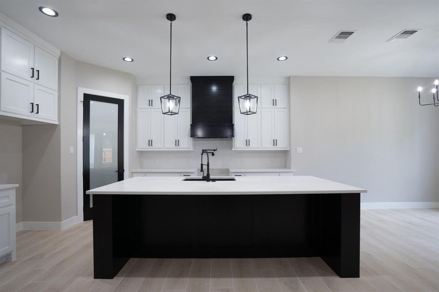 Quartz counter tops with shiplap vent hood and oversized kitchen island.