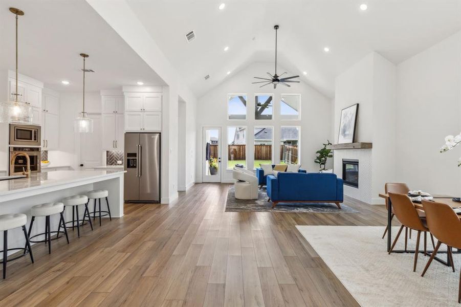 Living room featuring ceiling fan, light hardwood / wood-style flooring, sink, and high vaulted ceiling