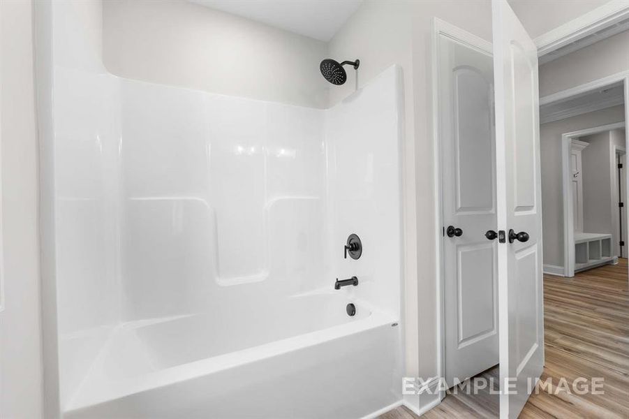 Bathroom with shower / bathing tub combination and hardwood / wood-style floors