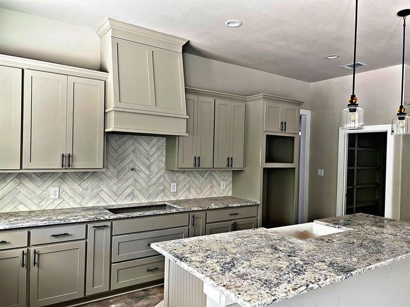 Kitchen with gray cabinetry, light stone counters, tasteful backsplash, decorative light fixtures, and dark hardwood / wood-style floors