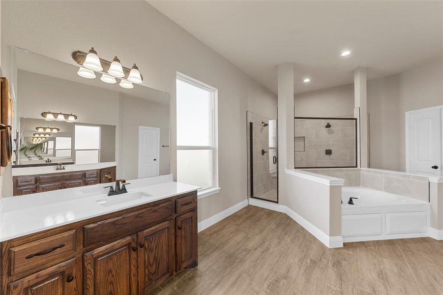 Bathroom featuring vanity, a healthy amount of sunlight, shower with separate bathtub, and hardwood / wood-style floors