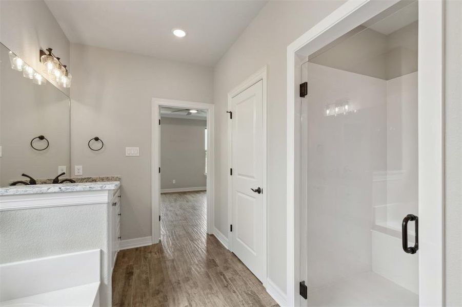 Bathroom featuring walk in shower, vanity, hardwood / wood-style floors, and ceiling fan