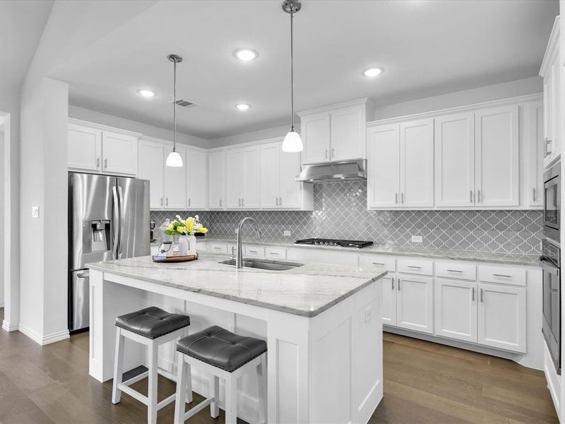 Kitchen featuring dark hardwood / wood-style floors, white cabinets, backsplash, and decorative light fixtures