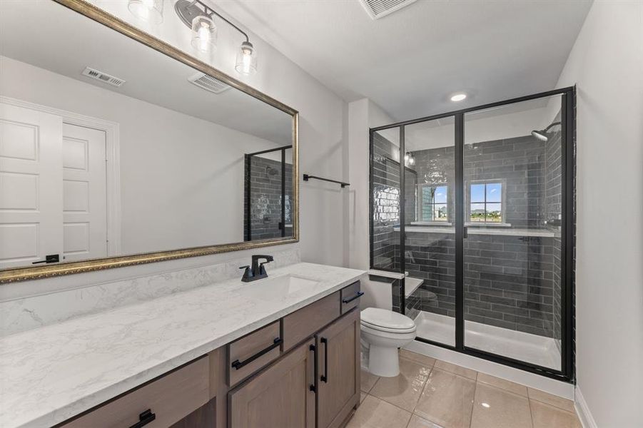 Bathroom with vanity, toilet, tile patterned floors, and a shower with shower door