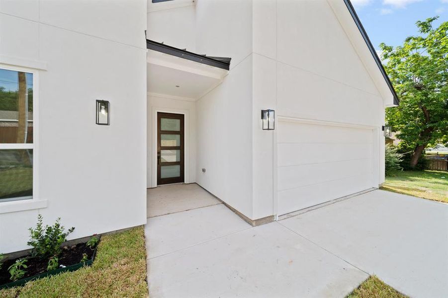 Property entrance featuring a garage and a patio