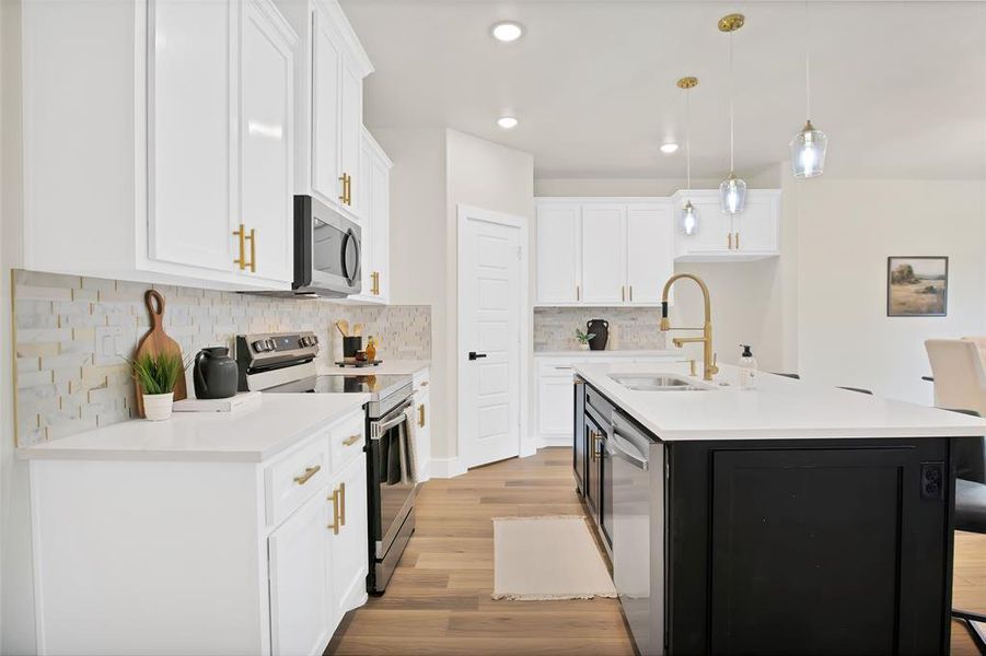 Kitchen with a kitchen island with sink, pendant lighting, white cabinetry, stainless steel appliances, and sink