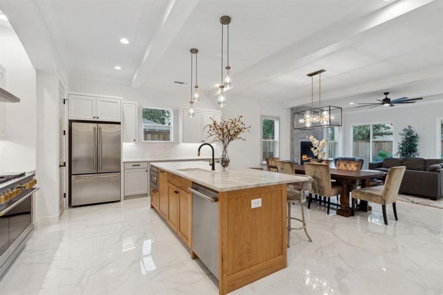 Kitchen with light stone counters, ceiling fan, sink, a kitchen island with sink, and stainless steel appliances