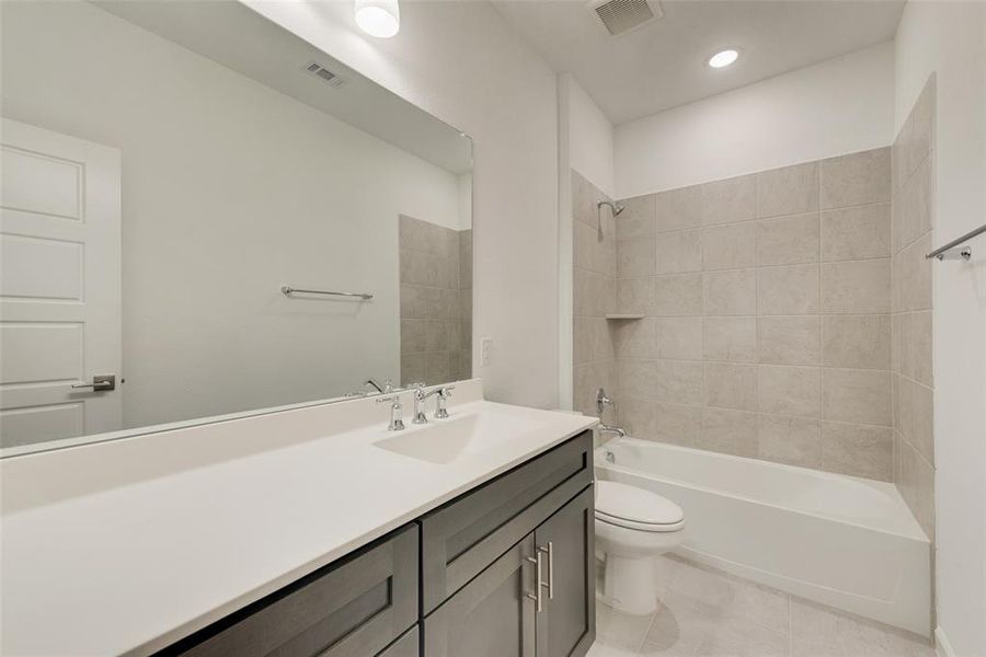 Full bathroom with tiled shower / bath, vanity, toilet, and tile patterned floors