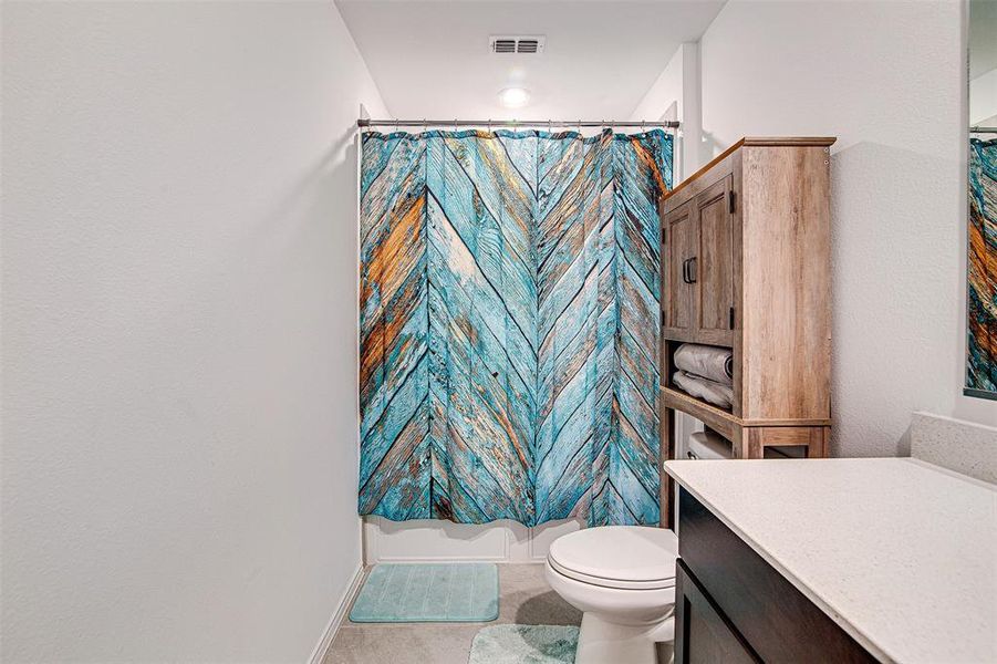 Bathroom with vanity, curtained shower, toilet, and tile patterned flooring