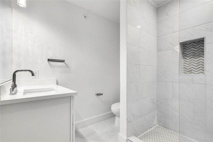 Bathroom with tile floors, tiled shower, toilet, and vanity
