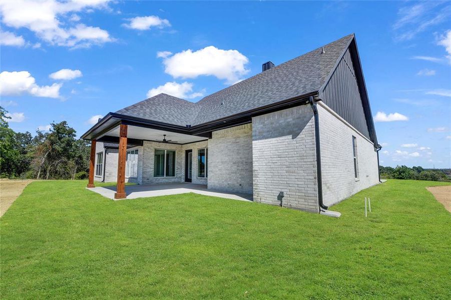 Rear view of house with ceiling fan, a patio area, and a yard