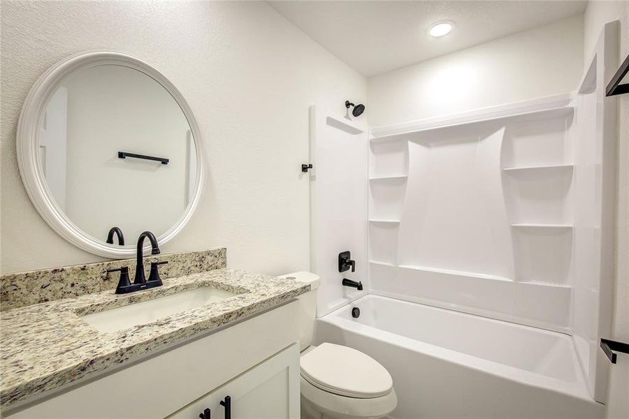 Full hallway bathroom with vanity with extensive cabinet space, toilet, and  shower combination