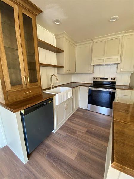 Kitchen featuring dark hardwood / wood-style floors, sink, stove, wooden counters, and dishwashing machine