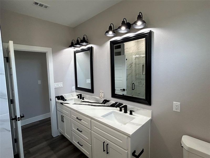 Bathroom featuring hardwood / wood-style floors, toilet, a shower with door, and vanity