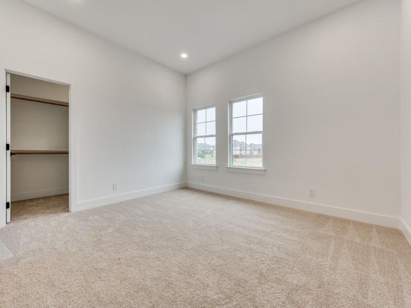 Unfurnished bedroom featuring light colored carpet, a walk in closet, and a closet