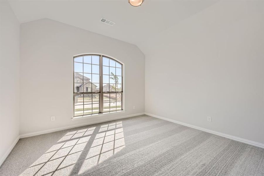 Empty room with lofted ceiling and light colored carpet