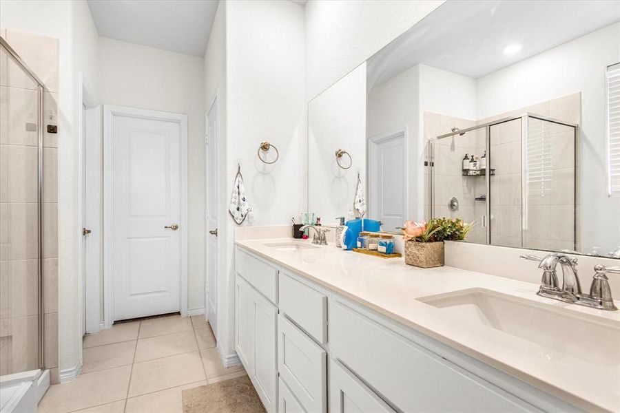 Bathroom with vanity, tile patterned flooring, and a shower with door