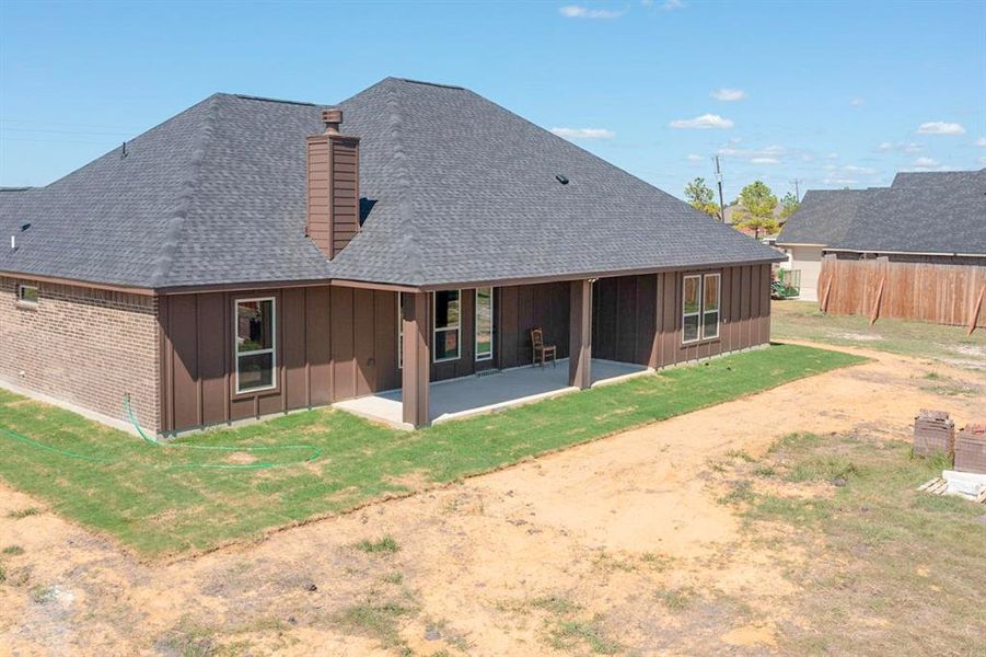 Back of house with a lawn and a patio