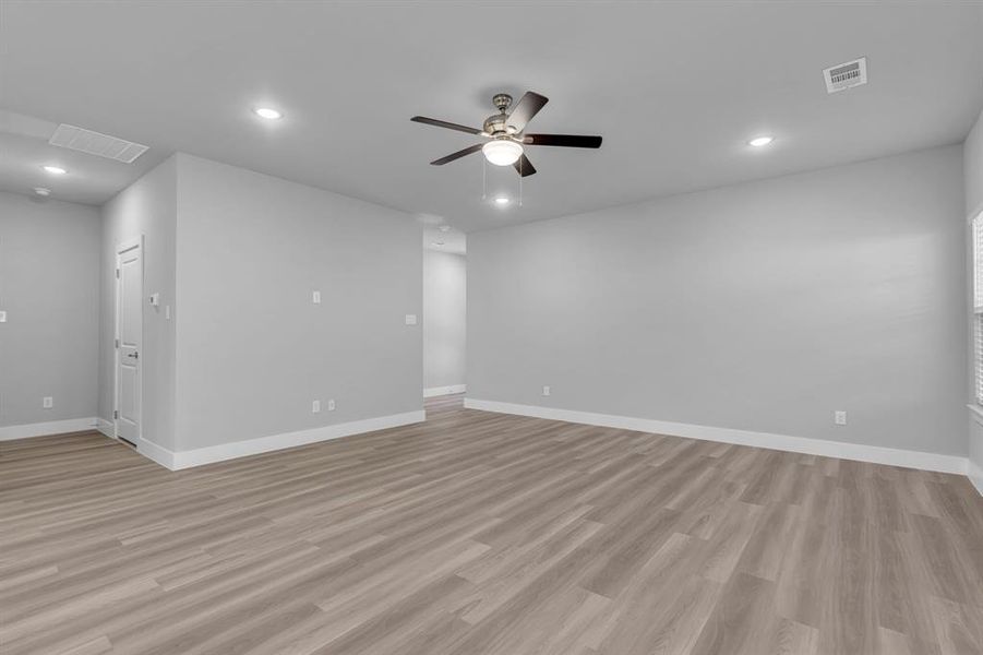 Empty room with ceiling fan and light hardwood / wood-style floors