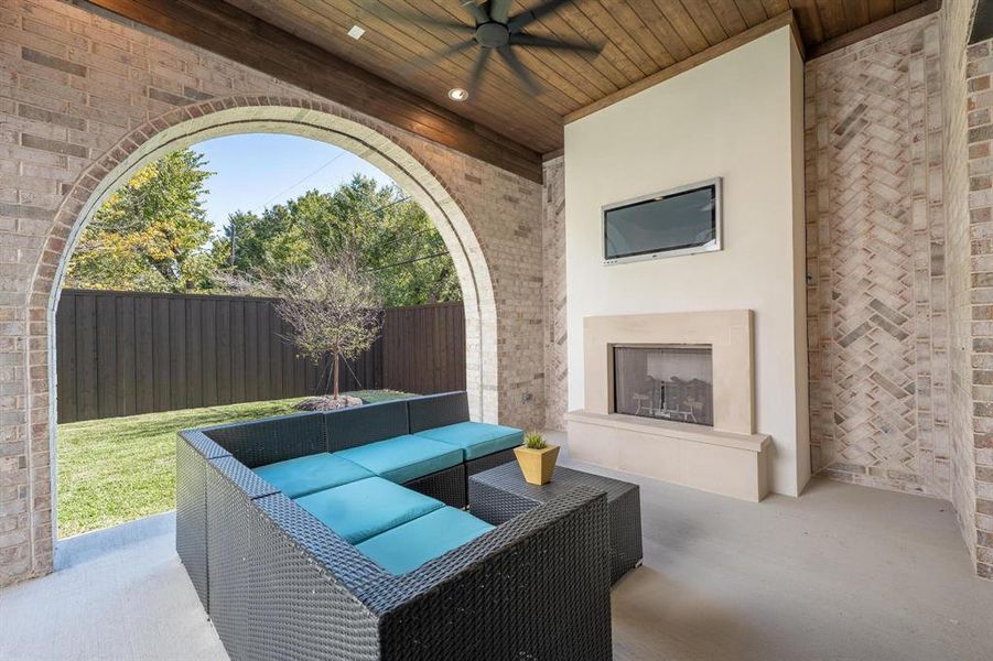 View of patio with an outdoor living space with a fireplace and ceiling fan and electric mosquito nets