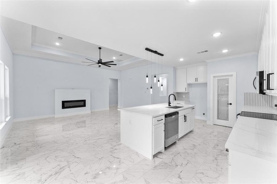 Kitchen with crown molding, stainless steel appliances, white cabinetry, a tray ceiling, and ceiling fan