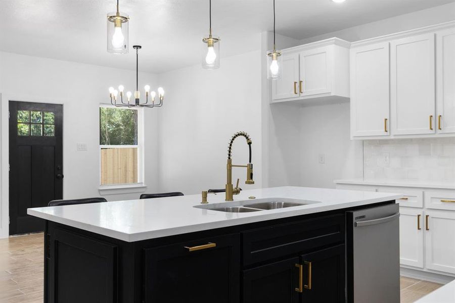 Kitchen with a center island with sink, sink, pendant lighting, stainless steel dishwasher, and decorative backsplash