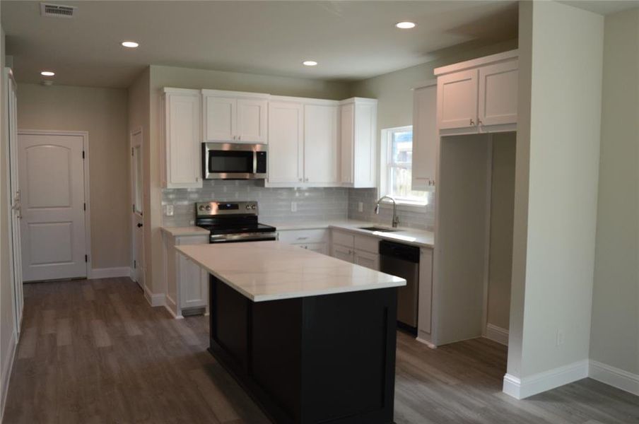 Kitchen with white cabinets, stainless steel appliances, and a kitchen island