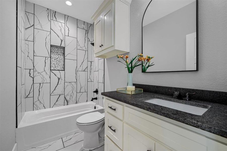 Full bathroom with tiled shower / bath, vanity, and toilet