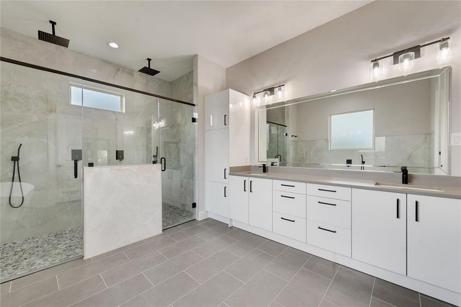 Bathroom with vanity, a shower with shower door, and tile patterned flooring